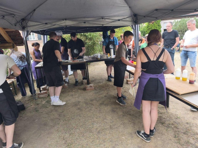 Helfer und Kunden beim Pizzaverkauf